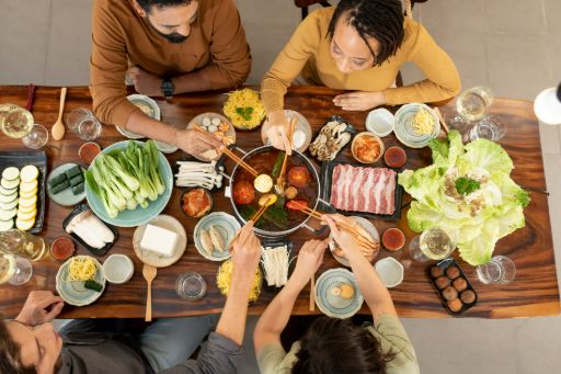 4 group of friends that are celebrating the Chinese New Year. There are a got pot with meat and vegetables