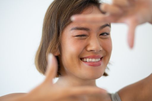 smiling asian woman loking at the camera making frame gesture